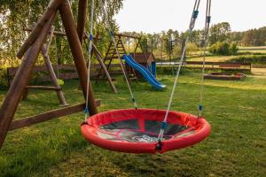 a red swing seat in a playground at Holiday House Folwark Jeleń in Poniklica