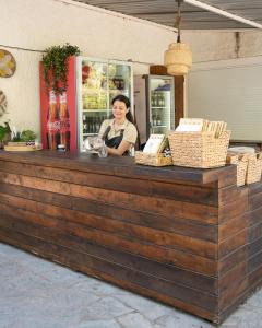 a woman is standing behind a wooden counter at Nisi Glamping in Paralia Rachon