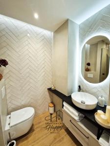a bathroom with a sink and a toilet and a mirror at Happy Deluxe ApartamentyHappy pl in Mielec