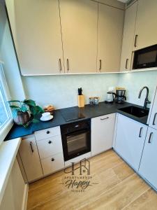 a kitchen with white cabinets and black counter tops at Happy Deluxe ApartamentyHappy pl in Mielec