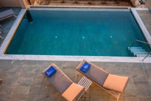 two chairs sitting next to a swimming pool at Moon and Sun in Vamos +64 photos