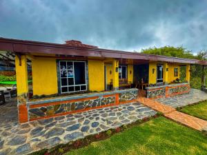 a yellow house with a stone pathway in front of it at Alojamiento EL GITANO in Filandia