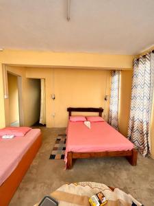 a room with two beds with pink sheets and windows at EcoDream Lodge in Hermitage Island
