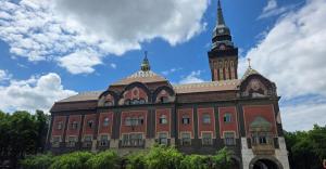 a large brick building with a clock tower on top at City Square, center in Subotica