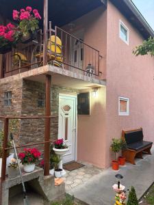 a pink house with a balcony and flowers in pots at Vikendica Bakino krilo in Železnička Stanica Apatin