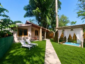 a yard with two chairs and a house at Caribbean Lory in Puerto Viejo