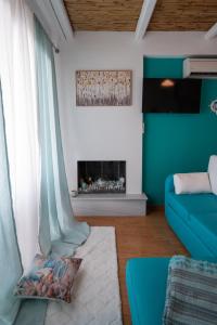 a living room with a blue couch and a fireplace at Kalypso Rental Apartment in Myloi +16 photos