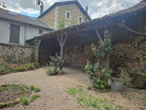 an old stone building with a wooden pergola at Private Apartment in Rochechouart