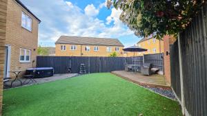 a backyard with a green lawn in front of a fence at Spacious and Modern 4BR with Hot Tub and Garden in Peterborough