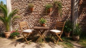a table and two chairs with plants on a brick wall at Quiet Mini Villa with Garden in Luxor +2 photos