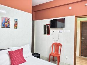 a bedroom with a bed and a red chair at Hotel Jyothi Kumar Royal ac rooms in Srikalahasti