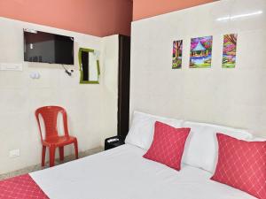 a bedroom with a bed and a red chair at Hotel Jyothi Kumar Royal ac rooms in Srikalahasti