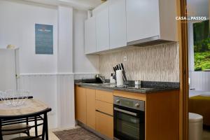 a kitchen with white cabinets and a small table at Casa dos Passos 1 in Guarda