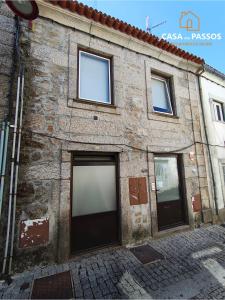 a stone building with two garage doors on a street at Casa dos Passos 1 in Guarda