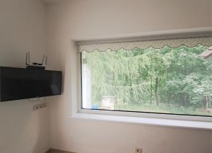 a room with a window with a flat screen tv at Cozy apartment in Jeruzalė in Vilnius