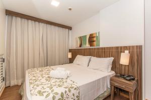 a hotel room with a bed and a nightstand with a white bedspread at Nobile Hotel em Brasília 97172 in Brasília