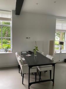 a dining room with a black table and white chairs at B&B Buitenplaats Natuurlijk Goed in Oosterwolde