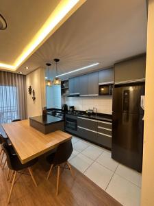 a kitchen with a wooden table and a black refrigerator at Resort com vista mar! in Barra Velha