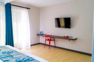 a bedroom with a red chair and a tv on a wall at Ngolu Hotel and Residences in Kitui