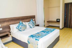 a bedroom with a large bed with blue pillows at Ngolu Hotel and Residences in Kitui +13 photos