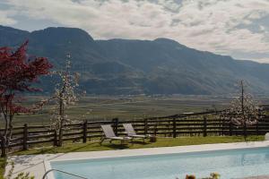 a swimming pool with two chairs and a view of mountains at Bucherhof in Marlengo