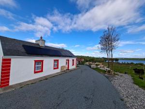 a white house with red windows and a road at Derryhick Escape in Crillaun