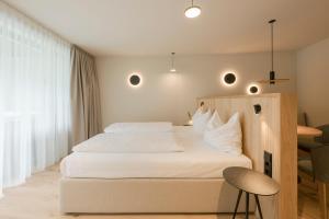 a bedroom with a white bed with a chair and a table at Amaris Suites Rabland, Südtirol in Rablà