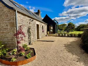 an external view of a stone house with a garden at Maison de Charme avec Spa Privatif & Jardin en Pleine Nature - Plages à moins de 20min in Guerlesquin