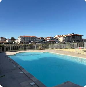 a large blue swimming pool with buildings in the background at Le Marin in Hossegor