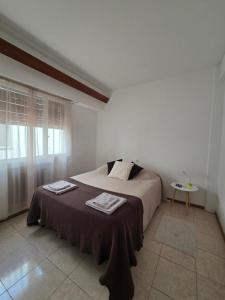 a bedroom with a bed and a table and a window at Casa LIDIA Hostel in Comodoro Rivadavia