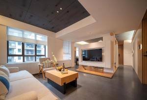 a living room with a couch and a tv at Zhangjiajie Utopia Hotel-New Hotel,English Speaking Host,Free Shuttle Service to East Gate of forest park,Free Fresh Coffee&Tea,Free Self-Service Laundry & Drying, Super-Large Swimming Pool,Tourism Service, Family and Group-friendly in Zhangjiajie