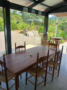 a wooden table with chairs and a large window at La casa de vidro in Tijucas