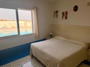 a bedroom with a bed and a window with a pool at Hotel Macondo in Lampedusa