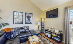 a living room with a black leather couch at The Safari Lodge in Osage Beach