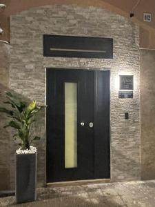 a black door in a brick wall with a potted plant at Mado Suite 112 in Bari
