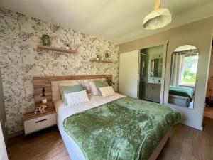 a bedroom with a large bed with a green blanket at L'Escale d'Armorique 1 in Languidic