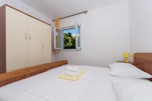 ein weißes Schlafzimmer mit einem Bett und einem Fenster in der Unterkunft Apartmani Gaube in Trogir
