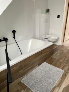 a white bathroom with a tub and a toilet at Duplex appartement in rustige woonwijk in Mortsel