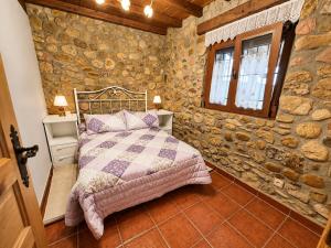 a bedroom with a bed in a stone wall at La Cochera del Abuelo in Medina de Pomar