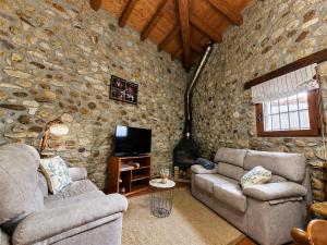 a living room with two couches and a stone wall at La Cochera del Abuelo in Medina de Pomar