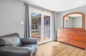 a living room with a chair and a dresser and a mirror at Eternal Sunrises in Sunrise Beach