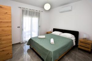a bedroom with a bed with a green blanket and white pillows at Stegna Holiday 2 in Archangelos