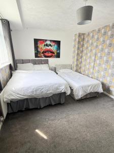 a bedroom with two beds and a painting on the wall at Families and Contractors Dudley DY1 in Lower Gornal +13 photos