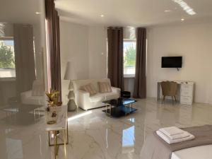 a white living room with a couch and a tv at Partenopeo Rooms & Suite in Nola