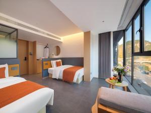 a hotel room with two beds and a window at Zhangjiajie Utopia Hotel-New Hotel,English Speaking Host,Free Shuttle Service to East Gate of forest park,Free Fresh Coffee&Tea,Free Self-Service Laundry & Drying, Super-Large Swimming Pool,Tourism Service, Family and Group-friendly in Zhangjiajie +99 photos