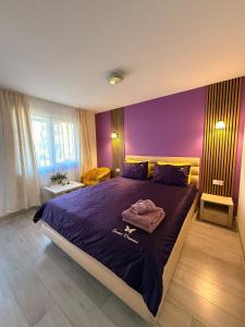 a bedroom with a large bed with purple walls at Sunset Expanse in Turda