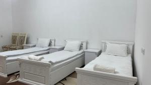 two beds in a room with white walls at Daniel SAMARKAND in Samarkand