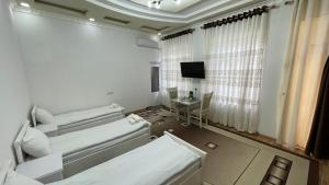 a white room with two beds and a television at Daniel SAMARKAND in Samarkand