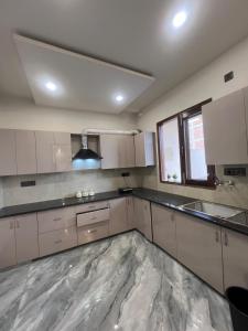 a kitchen with white cabinets and a large marble floor at Starlight villa in Ghaziabad