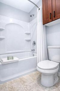 a white bathroom with a toilet and a bath tub at Annabell Gardens in Lincoln